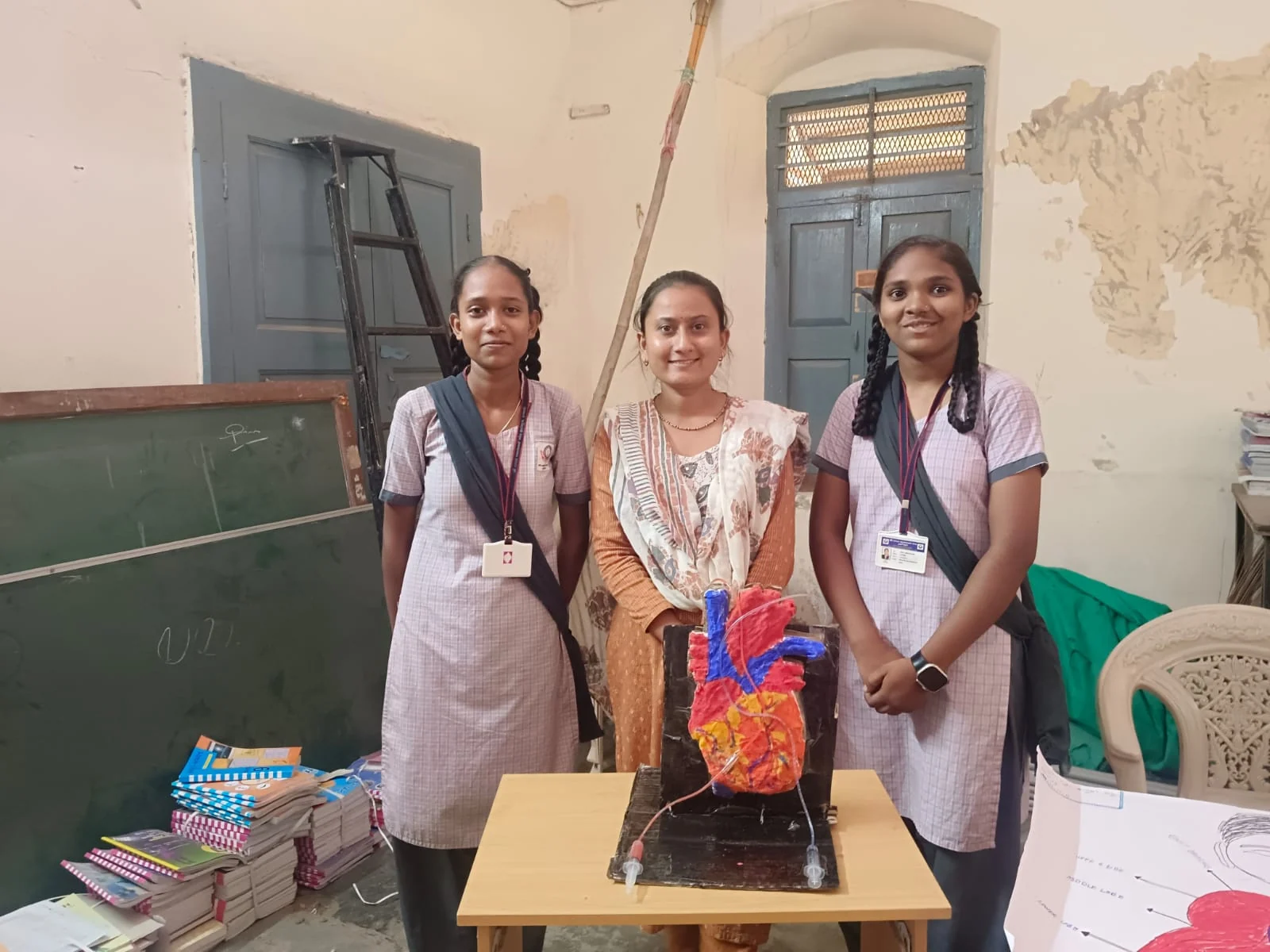 An educator and two schoolgirls presenting a human anatomy model